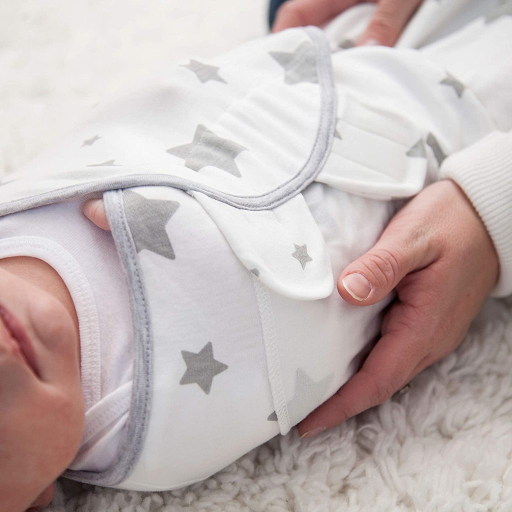 Baby in weißem Pucksack mit grauen Sternen.
